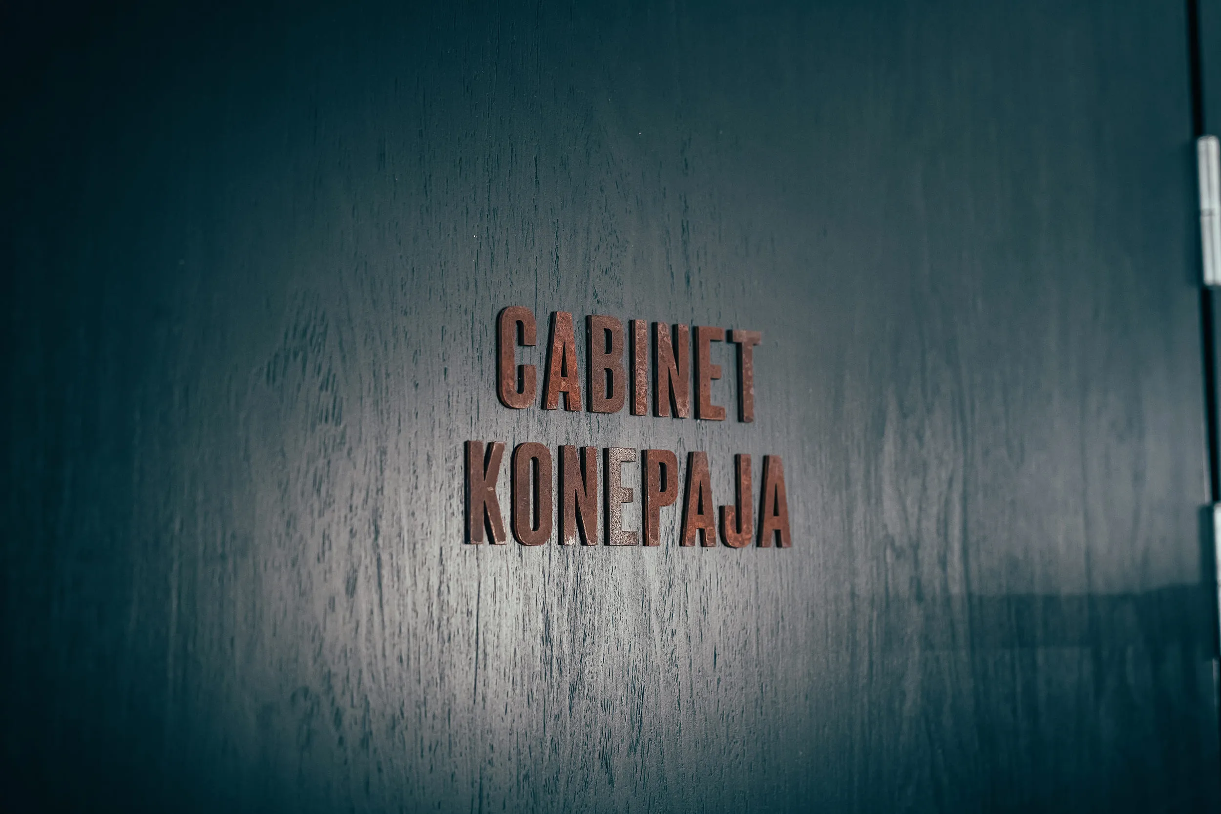 Rust-colored sign on a dark wall reads 'GABINET KONFERENCYJNY' (conference room) in bold letters.